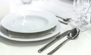 A place setting with a spoon, knife, glass, and plate