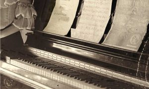 Black and white photo of piano with sheet music for short story by Rona Arato