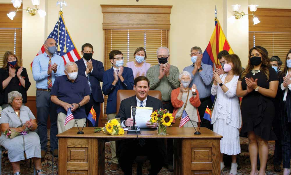 Holocaust survivors, students and lawmakers gather around Arizona Governor Doug Ducey in August 2021 as he signs House Bill 2241.