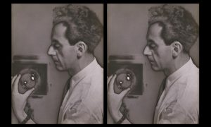 Two side by side self portraits of Man Ray in profile, intently adjusting the focal range on his view camera as if for a portrait session. He directs the camera in the photograph at the audience, while the camera taking his picture remains invisible.