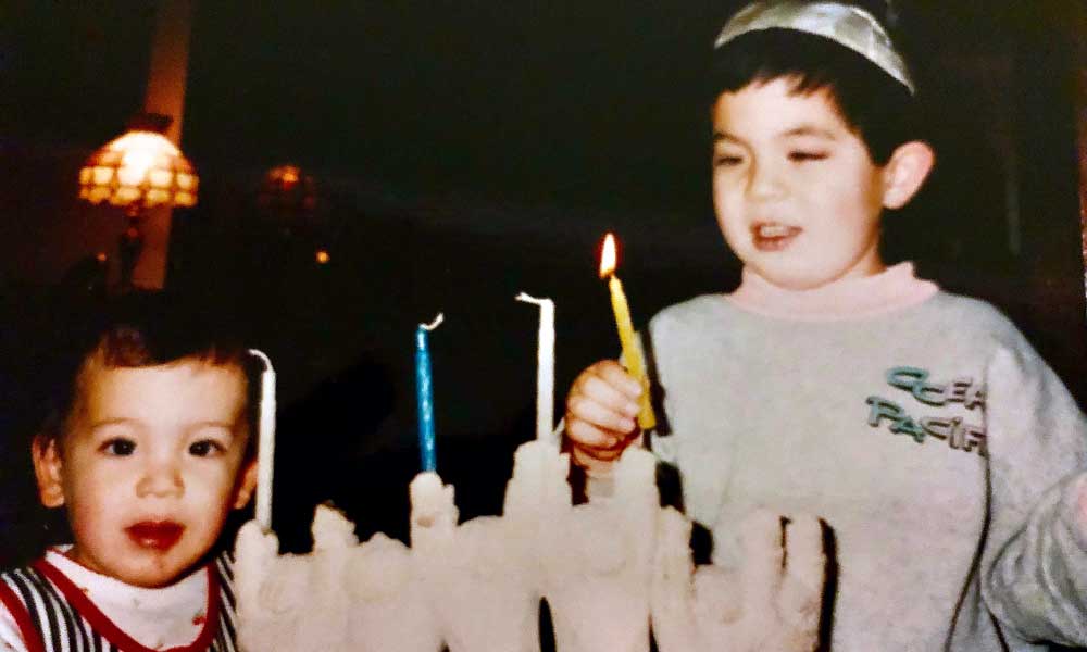 LUNAR filmmaker Jared Chiang-Zeizel lights a Hanukkah menorah with his brother.