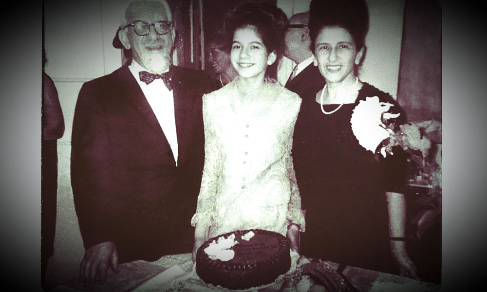 Susannah Heschel stands between her two parents behind a cake at her bat mitzvah