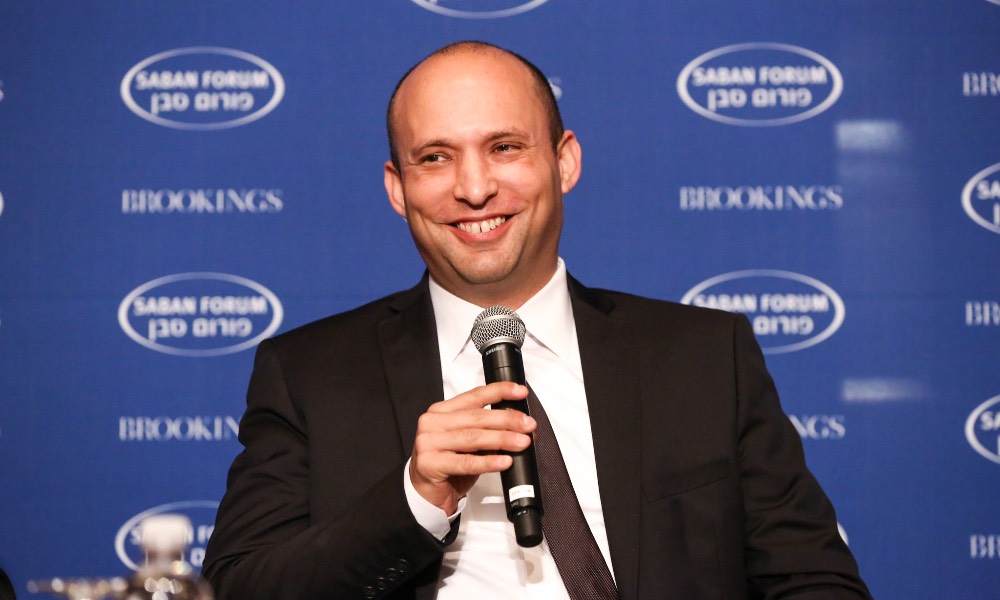 Naftali Bennett holding a microphone at a press conference