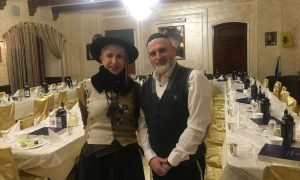 a rabbi and his wife stand in front of tables set for Passover