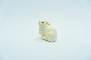 a small, porcelin netsuke bunny with its paw raised