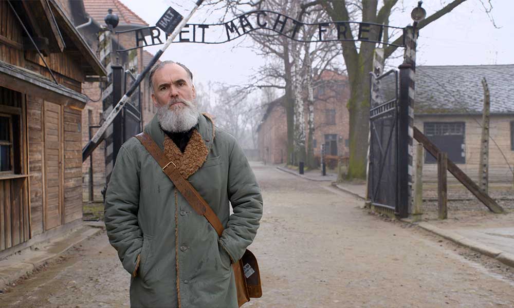 David Wilkinson blankly posing at the Auschwitz gates