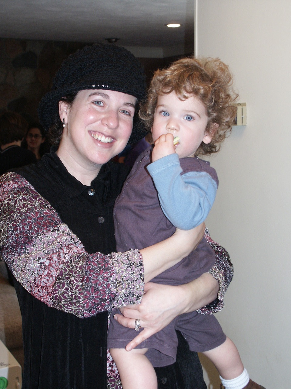 An orthodox jewish woman smiles and holds her young son.