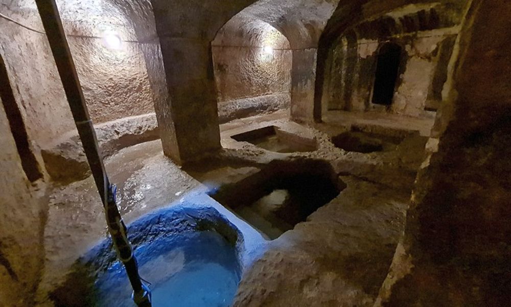 A low-lit stone chamber with four small pools used for ritual bathing inside.