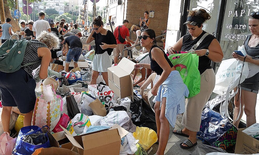 A crowd of Israeli volunteers look through boxes and bags of donations.
