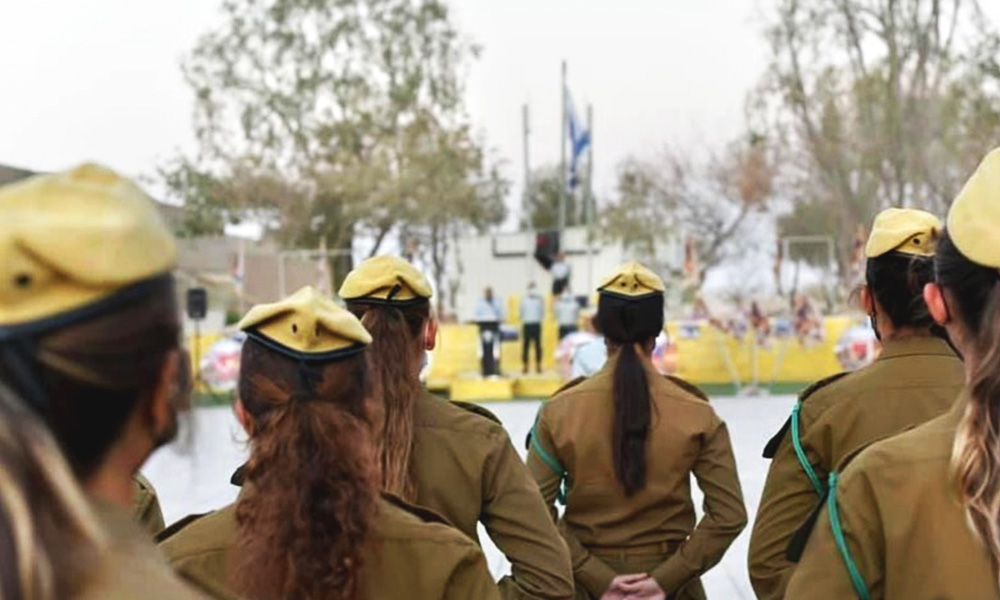 Six women in olive green uniforms and yellow berets stand with their backs to the camera as part of an IDF "changing of the guard" ceremony for the head of the IDF spotters unit.