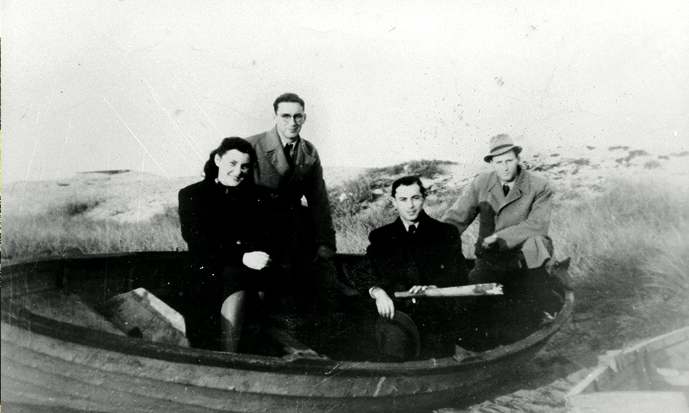 Four adult siblings in a boat, on land.
