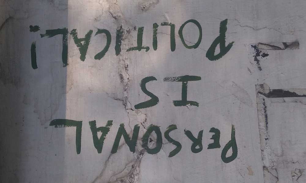 "Reasonal is Political" written upside down on a concrete wall in green paint