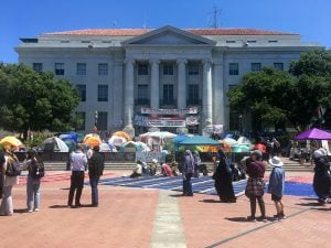 Sproul Hall, a neoclassical building at University of California, Berkeley, with a pro-Palestinian encampment infront and people roaming around it.
