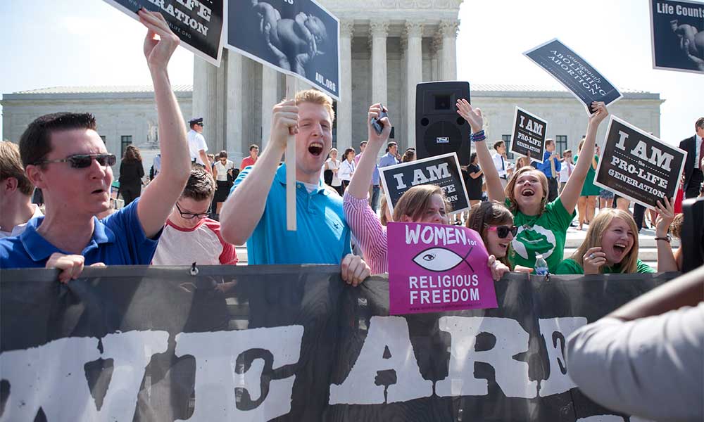A group of young evangelicals demonstrate against abortion rights in front of the Lincoln Memorial, holding signs.