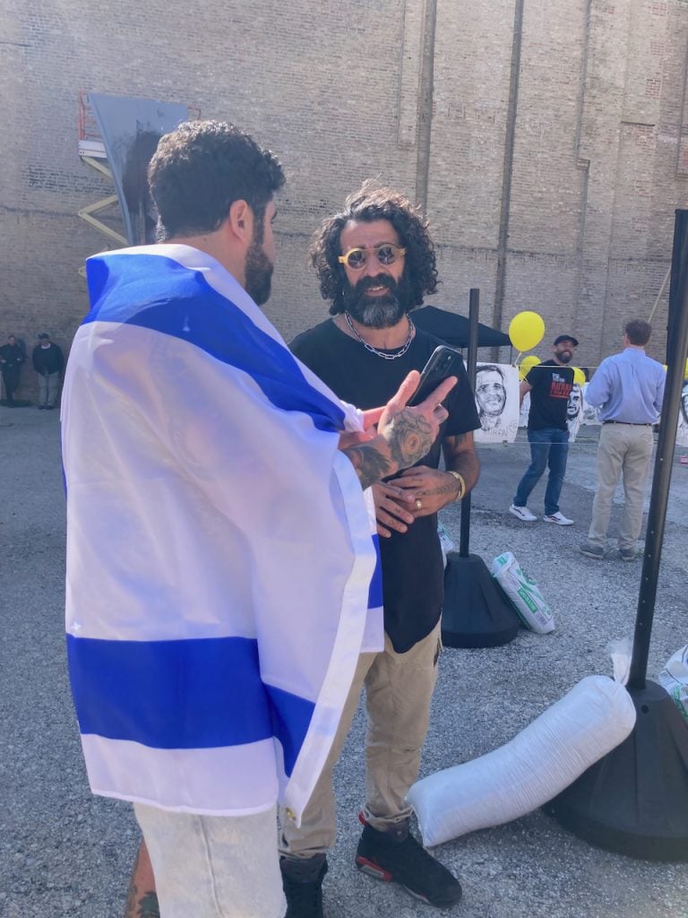Tomer Peretz talks to a man in Israeli flag